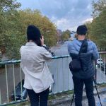 Zwei Menschen auf einer Brücke beim Fotografieren.