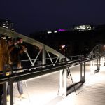 2 Menschen bei Nacht auf einer Brücke mit Stativ und Kamera, im Hintergrund die beleuchtete Kuppel des Altonaer Fischmarkts